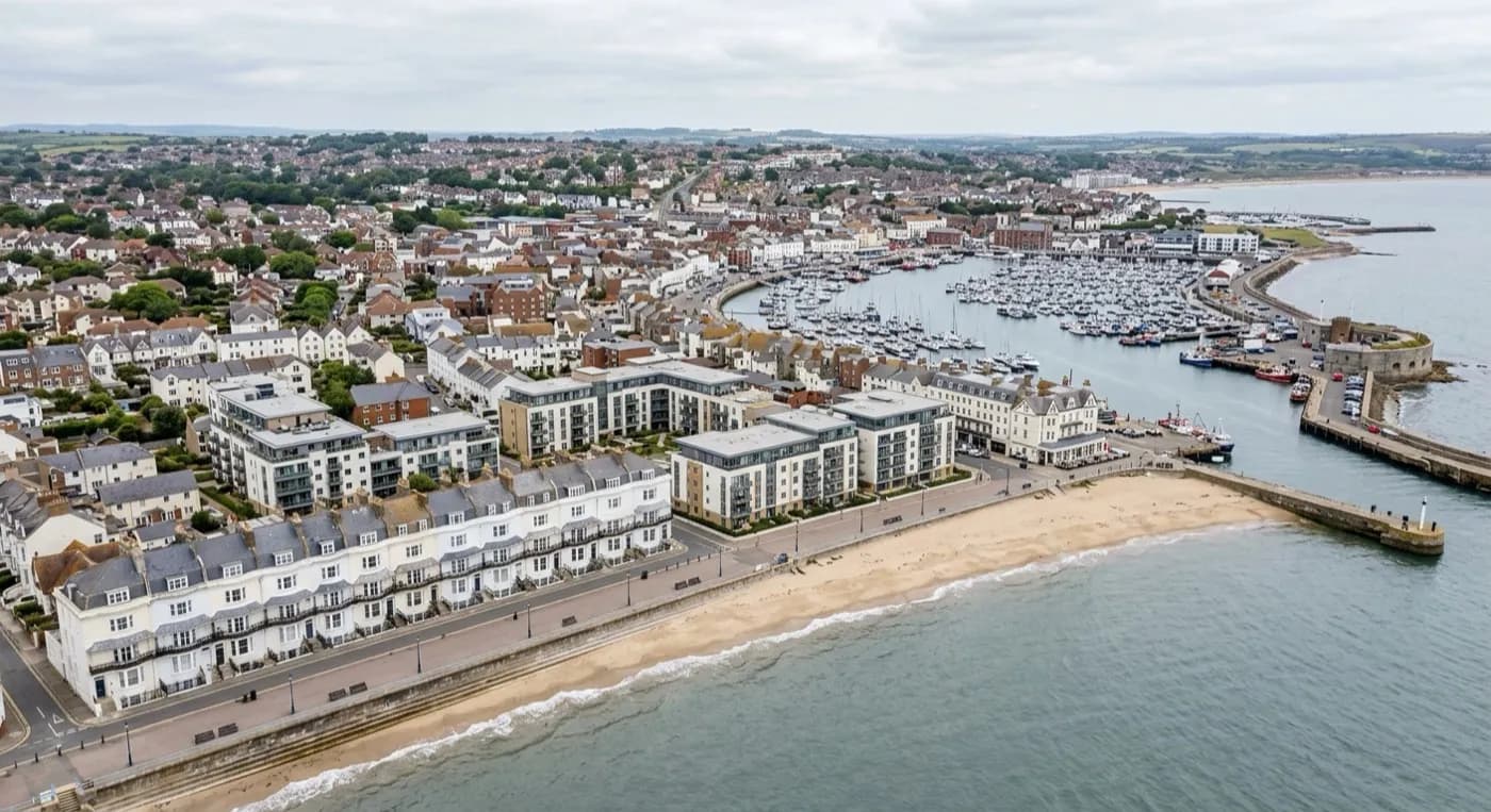 Aerial view of a South West coastal seafront with a mix of period terraces and modern flat-roofed apartment blocks